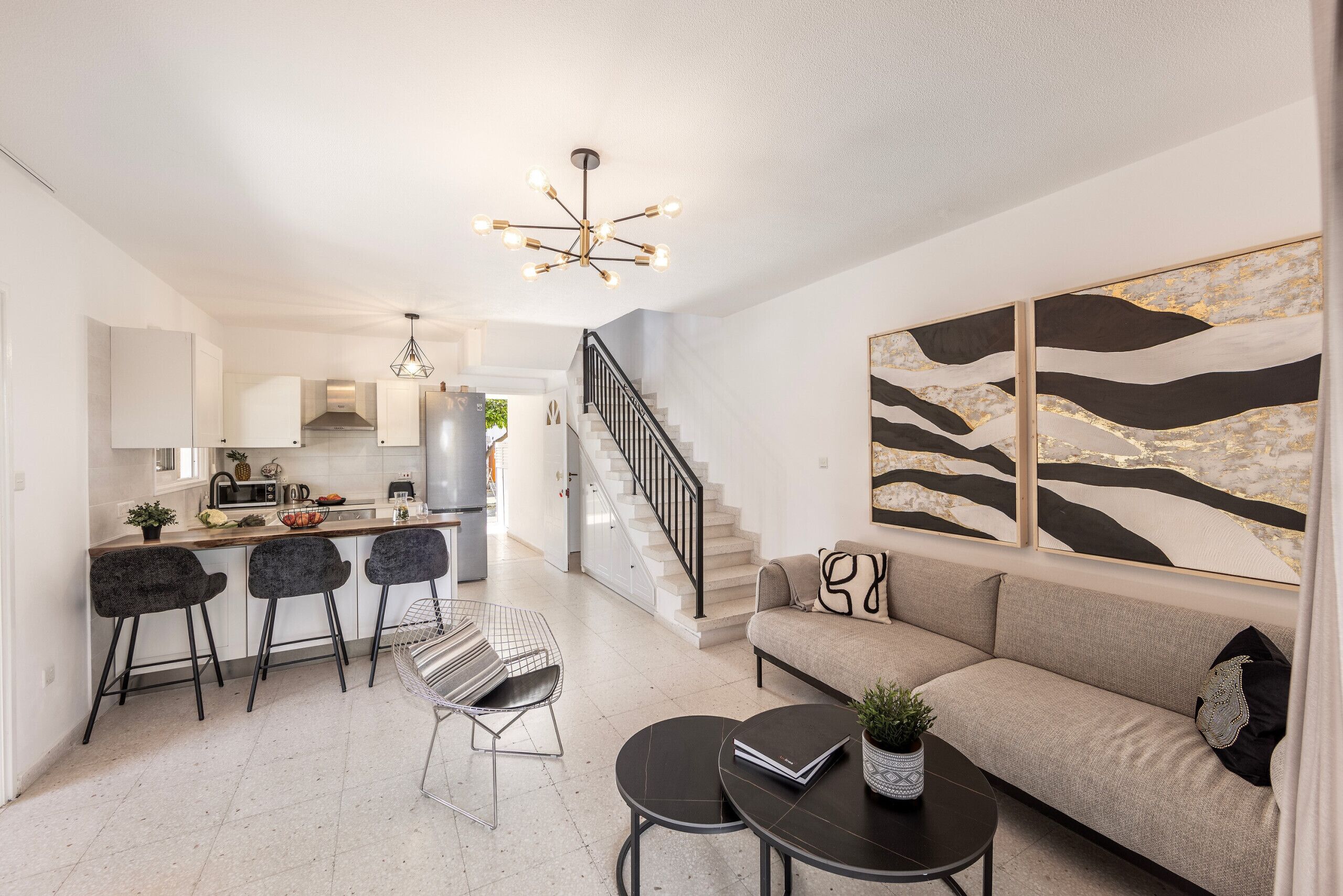 A modern kitchen with a central island, bar stools, and a dining area with a round table.