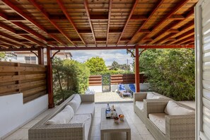 An outdoor patio with wicker furniture, a table with drinks, and a view of the backyard. - Larnaca Seaside Villa Marina 44 (Pervolia)