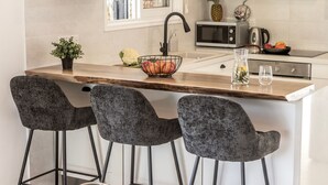 A kitchen with a central island, bar stools, a sink, and a microwave. - Larnaca Seaside Villa Marina 44 (Pervolia)