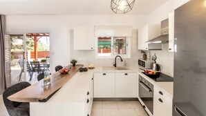 A modern kitchen with white cabinets, a wooden countertop, a stainless steel refrigerator, and a window overlooking a patio area. - Larnaca Seaside Villa Marina 44 (Pervolia)