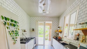 A modern kitchen with white cabinets, a black and white checkered floor, and a ceiling fan. - Casa c Wifi Churrasq Pisc red rio Pet Friendly (Benevides)