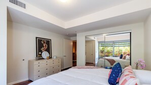Une chambre à coucher avec un grand lit, une commode, un miroir et une fenêtre donnant sur l’extérieur.