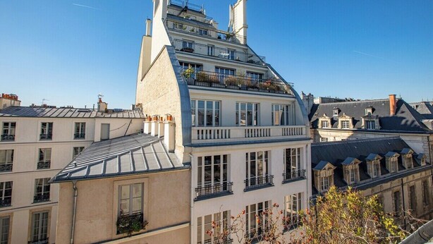 Un edificio de varios pisos con balcones, ventanas grandes y un cielo despejado.