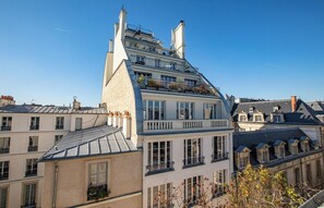 Un immeuble à plusieurs étages doté de balcons, de grandes fenêtres et surplombant un ciel dégagé.