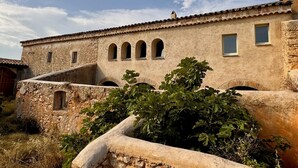 A rustic building with a stone facade, multiple arched windows, and a tiled roof. - Haven of peace in the Garraf: 18th-century masia, sea view & exceptional light (Olivella)