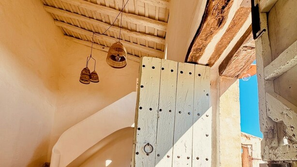 A rustic wooden door with a metal latch, a stone staircase leading to an upper level, and a woven basket hanging from the ceiling. - Haven of peace in the Garraf: 18th-century masia, sea view & exceptional light (Olivella)