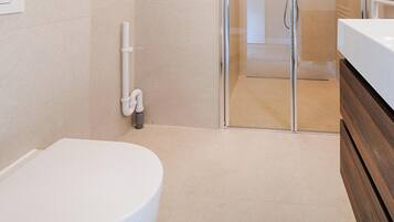 Een moderne badkamer met toilet, douche en douchecabine met glazen wanden.