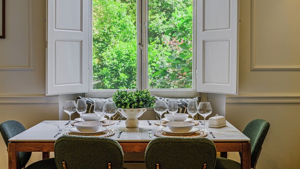 Een eettafel voor zes personen, met uitzicht op groen buiten het raam.