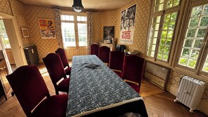 Ein Esszimmer mit einem langen Tisch, roten Stühlen, einem Heizkörper und Postern an den Wänden.