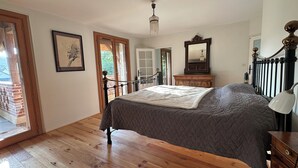 A bedroom with a bed, wooden floor, a door leading outside, a dresser, a mirror, and a chandelier. - Unique. "Villa fleurie" on the Fontainecourt estate with artists' studios. (Glos-sur-Risle)