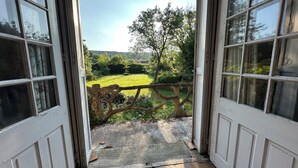 A view from a room with a wooden deck leading to a grassy field, with a tree and a fence in the background. - Unique. "Villa fleurie" on the Fontainecourt estate with artists' studios. (Glos-sur-Risle)