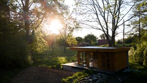 A small wooden structure with a glass door, surrounded by greenery and trees. - Unique. "Villa fleurie" on the Fontainecourt estate with artists' studios. (Glos-sur-Risle)
