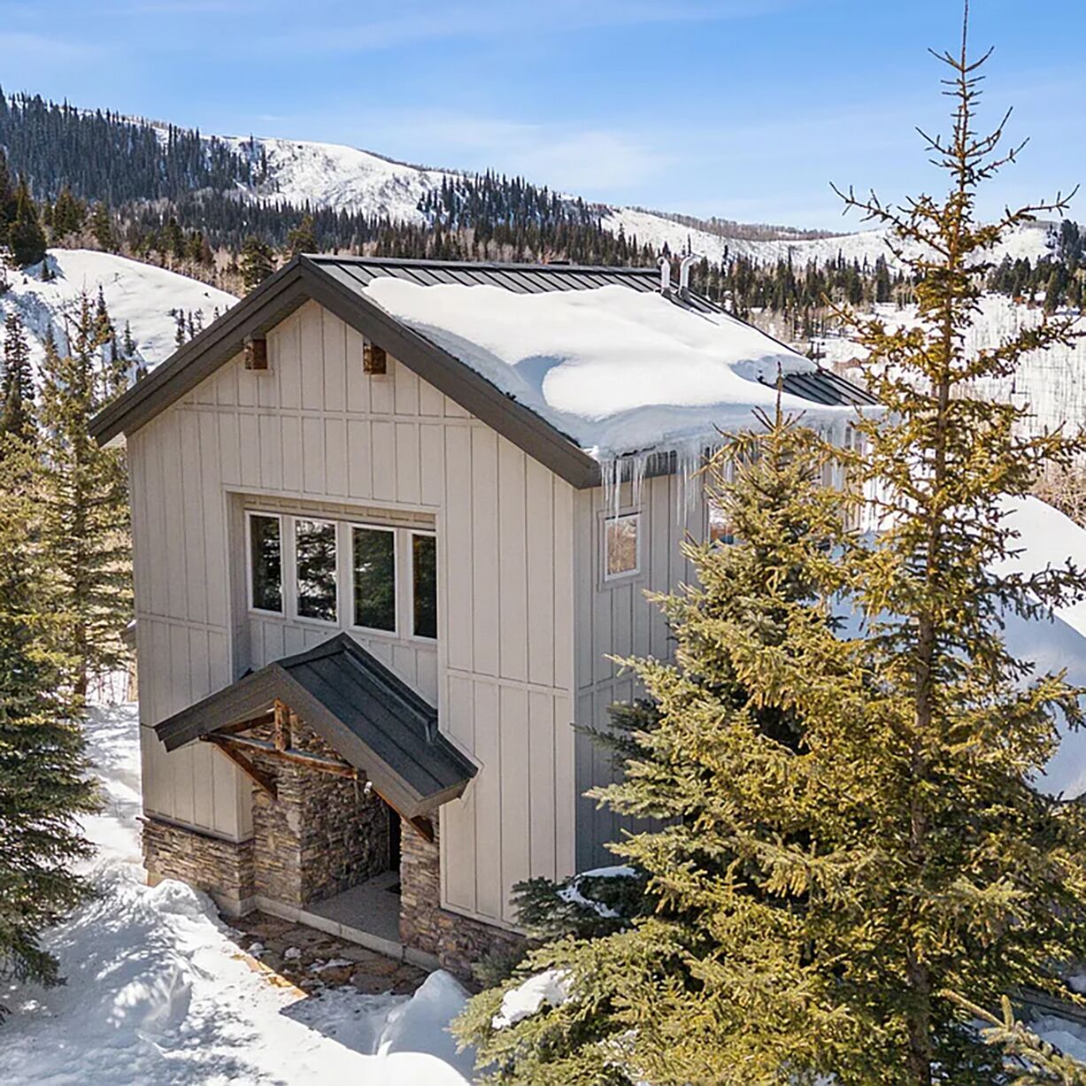 A cabin with a stone foundation, a pitched roof, and a window.
