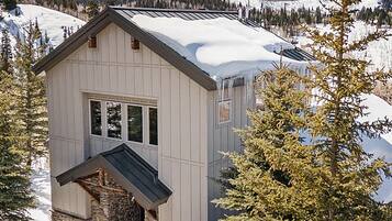 A cabin with a stone foundation, a pitched roof, and a window.