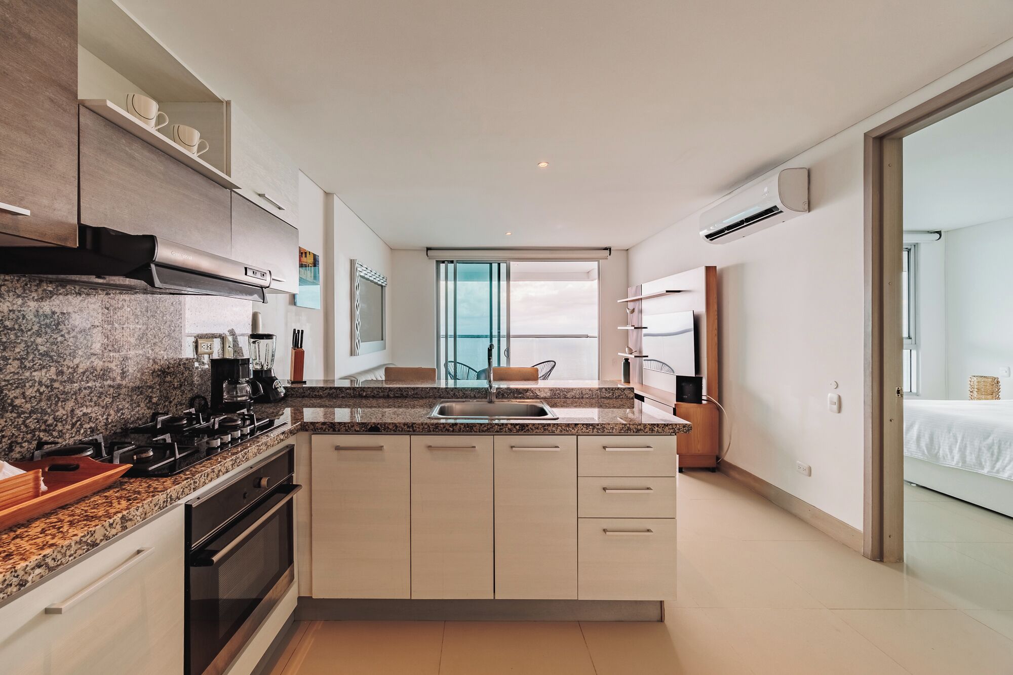 A modern kitchen with granite countertops, a built-in oven, and a large island with a sink.