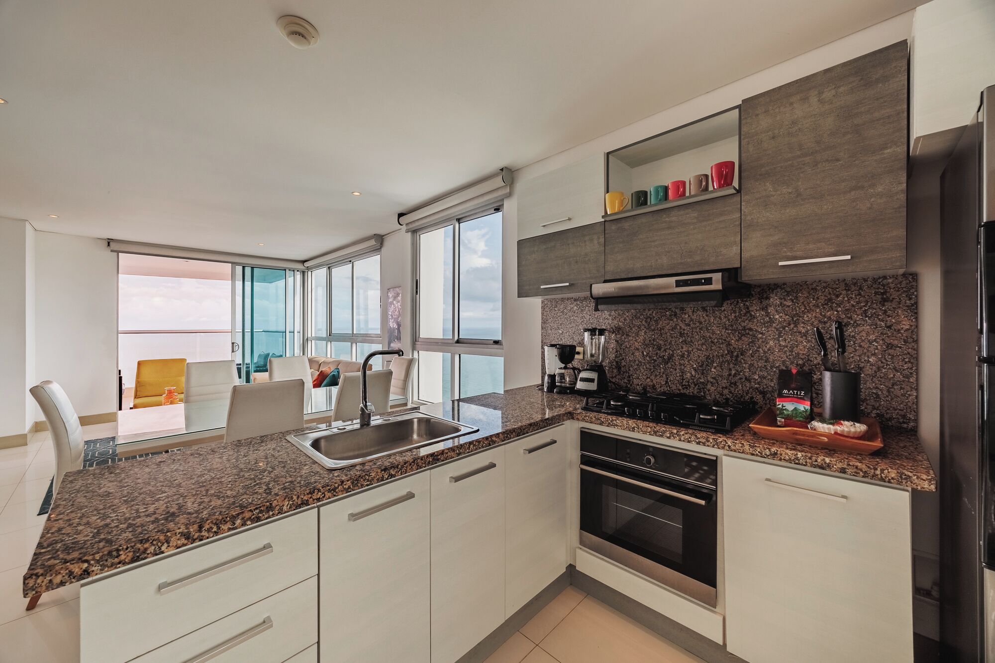 A modern kitchen with granite countertops, stainless steel appliances, and a view to the outside.