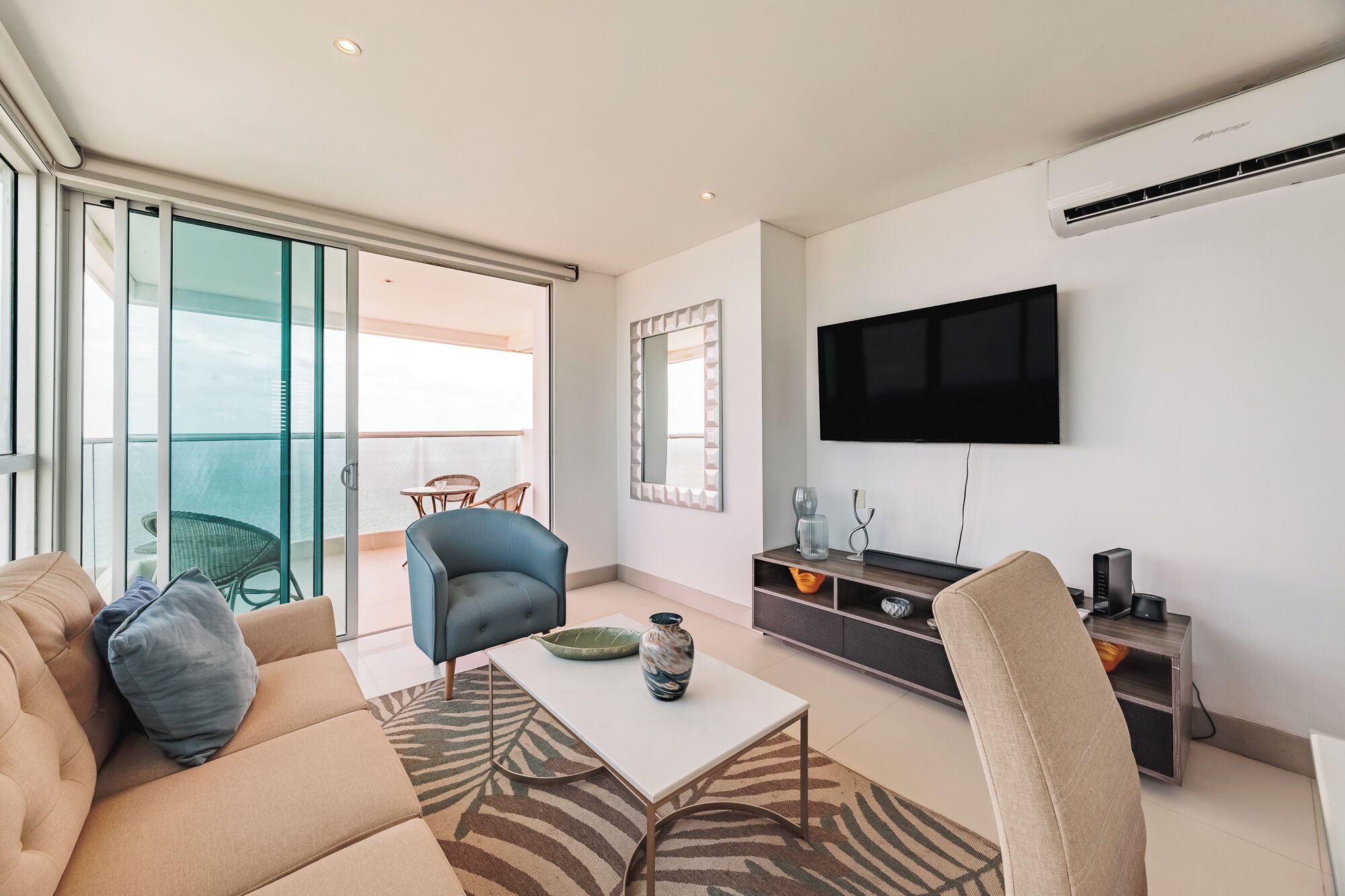 Un salon moderne avec un canapé, une table basse, un téléviseur et un balcon offrant une vue agréable.