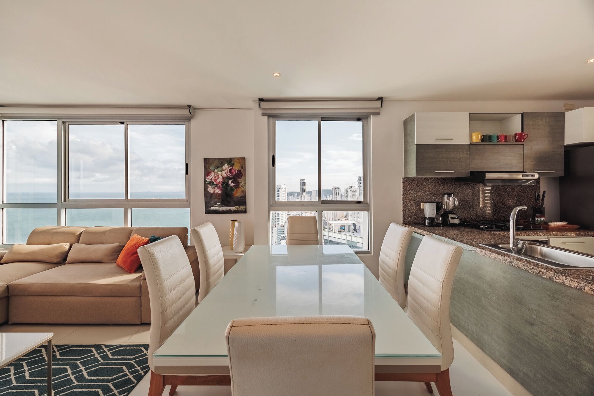 A modern apartment with a dining area, kitchen, and a balcony with a city view.