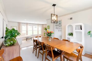 Un comedor moderno con una mesa y sillas de madera, una lámpara colgante y una planta en maceta.