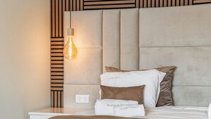 Un lit bien fait, avec une tête de lit, des oreillers et une couverture.
