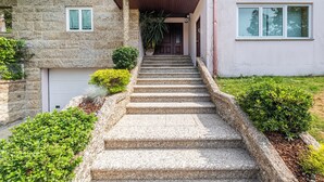 Une maison avec une façade en pierre, un porche à l’avant et un escalier en pierre menant à une porte en bois.