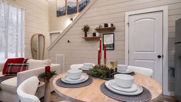 Un comedor acogedor con una mesa de madera dispuesta para cuatro personas, rodeada de sillas blancas.