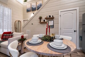 A cozy dining area with a wooden table set for four, surrounded by white chairs.