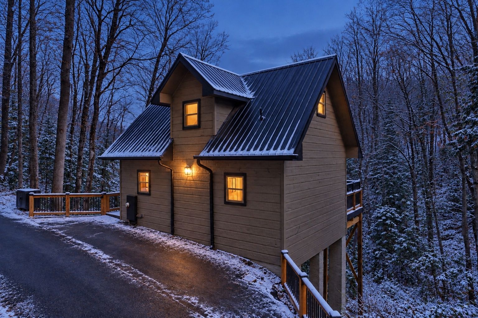 A two-story wooden cabin with a metal roof, surrounded by snow-covered trees.