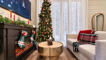 Un saló acollidor amb una llar de foc, un arbre de Nadal, un sofà i una televisió.