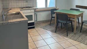 Cozinha moderna com fogão embutido, pia e área de jantar com mesa e cadeiras.