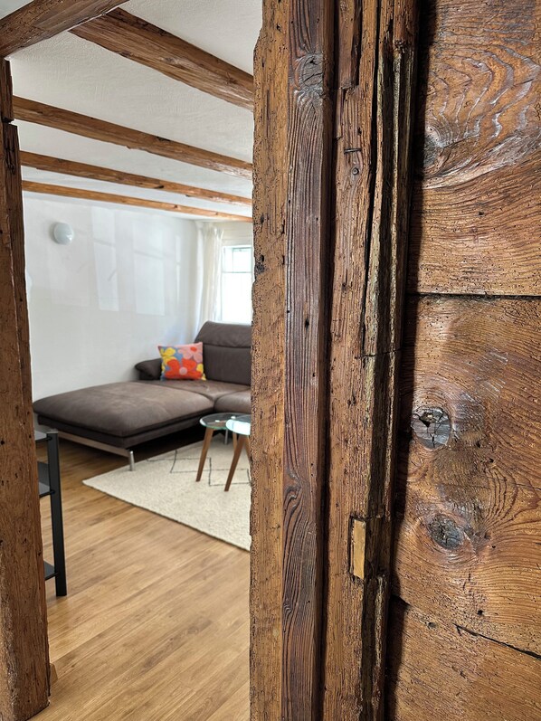 A room with exposed wooden beams, a sofa, a small table, and a glass coffee table. - Charming vacation apartment on the lakefront (Arbon)