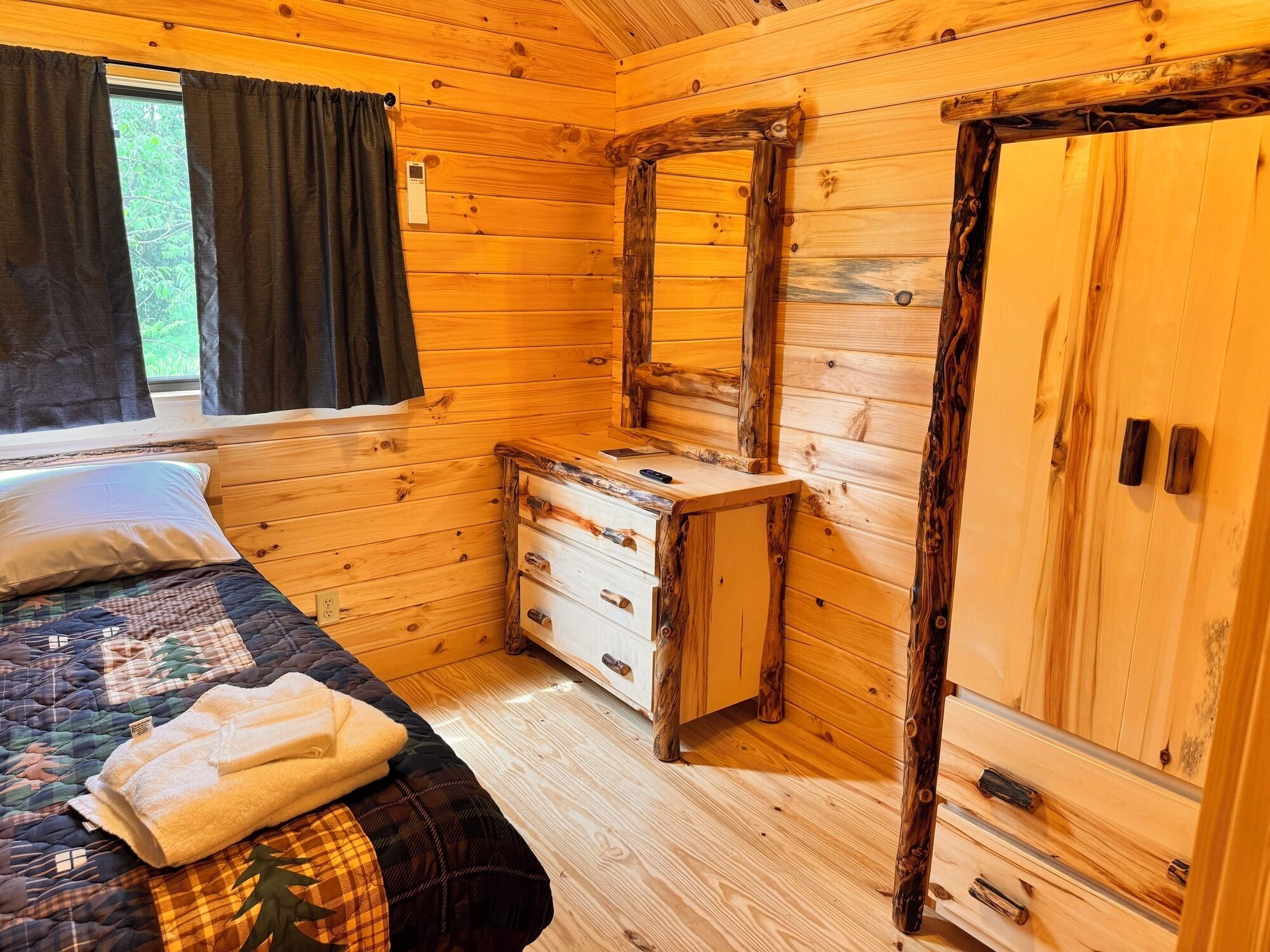 Une chambre dans une cabane en bois, comprenant un lit, une commode, un miroir et une armoire.