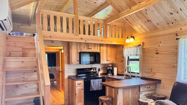 Interno di una baita in legno con cucina, zona pranzo e un angolo salotto accogliente.