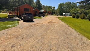 Una strada sterrata conduce a delle baite di legno, con camper parcheggiati nelle vicinanze.