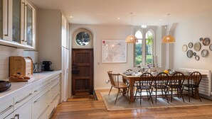 Una cocina con armarios de madera, una mesa de comedor para seis personas y un ventanal con vistas a zonas verdes.