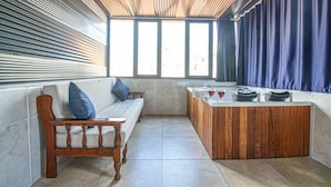 A modern room with a wooden bench, a sofa with blue cushions, a wooden counter, and large windows with curtains. - Mitani Suites (Istanbul)