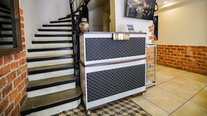 A reception area with a staircase, a reception desk, a television, and a brick wall. - Mitani Suites (Istanbul)