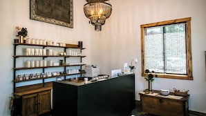 A reception area with a wooden counter, shelves with products, a chandelier, and a window with a view.