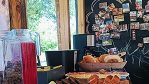 A buffet table with various food items, a coffee machine, and a wall decorated with photos. - Refugio Silvestre (Molina)