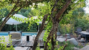 A wooden deck with outdoor furniture, a pool, and a pergola with a white umbrella. - Refugio Silvestre (Molina)