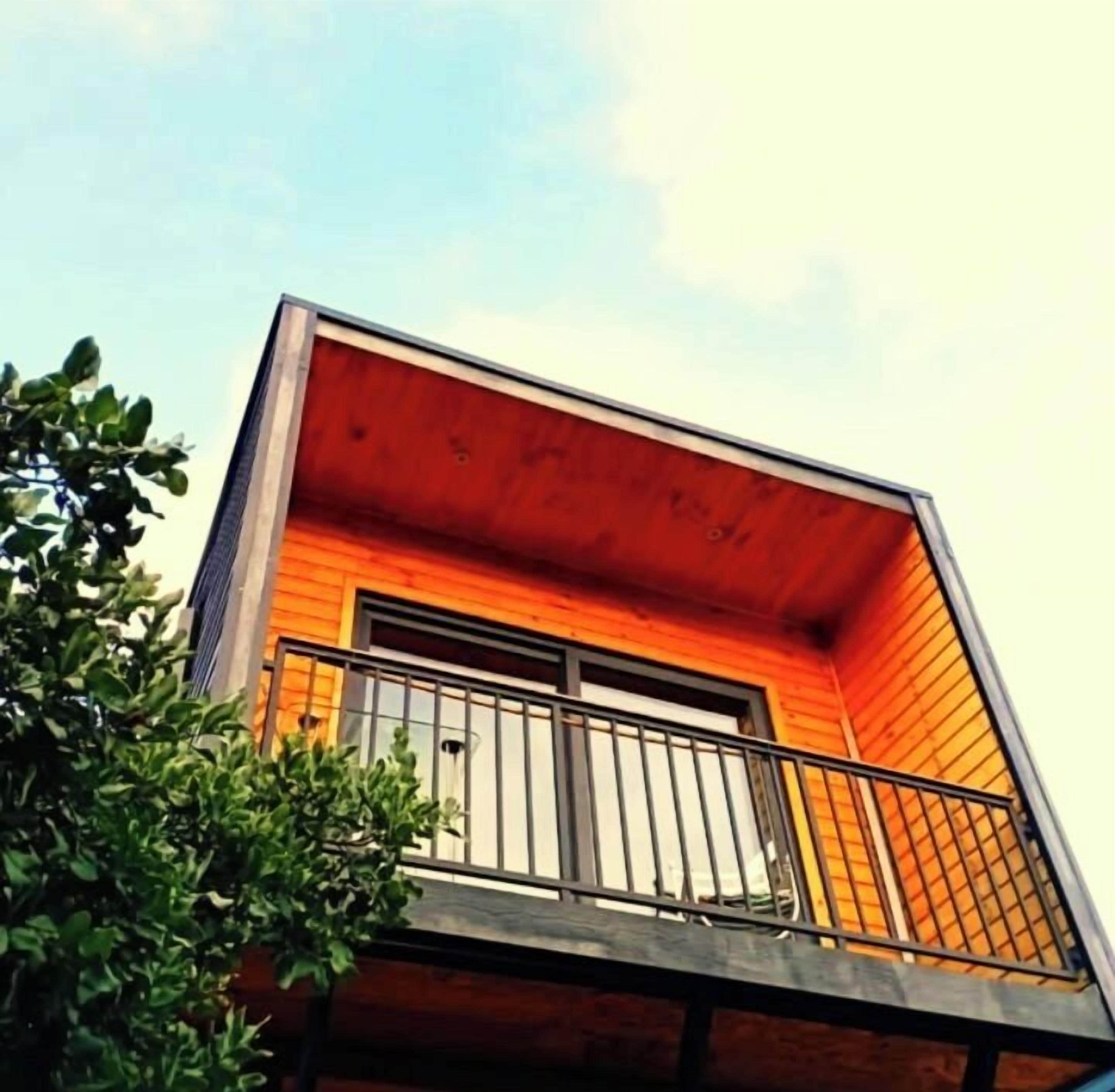 A modern building with a wooden facade and a balcony with a metal railing.