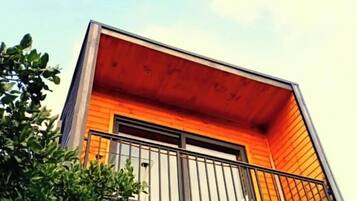 A modern building with a wooden facade and a balcony with a metal railing.