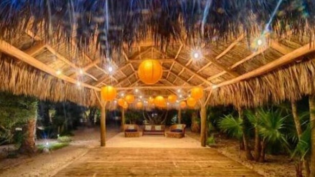 An indoor wooden structure with a thatched roof, multiple hanging spherical lights, and a central seating area. - Islamorada Suite With Kayaks •Patio & Garden Views - Wildflower Suite (Islamorada)
