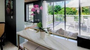 A modern room with a large sliding glass door leading to an outdoor area with a pool and chairs. - Islamorada Suite With Kayaks •Patio & Garden Views - Wildflower Suite (Islamorada)