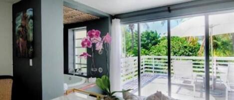 Una habitación moderna con un amplio ventanal corredero que da a un área exterior con piscina y sillas.