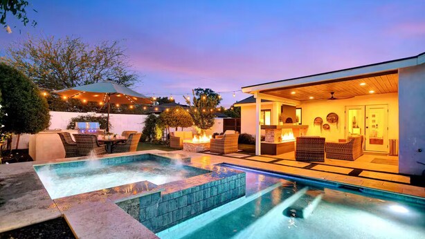 A pool area with a hot tub, outdoor seating, and string lights.