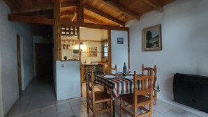 A dining area with a table set for four, wooden chairs, a striped tablecloth, and a painting on the wall.