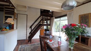 A dining area with a wooden table, chairs, a vase of flowers, and a staircase leading to an upper level. - Holiday Home in Noordwijkerhout by Forest & Lake (Noordwijkerhout)