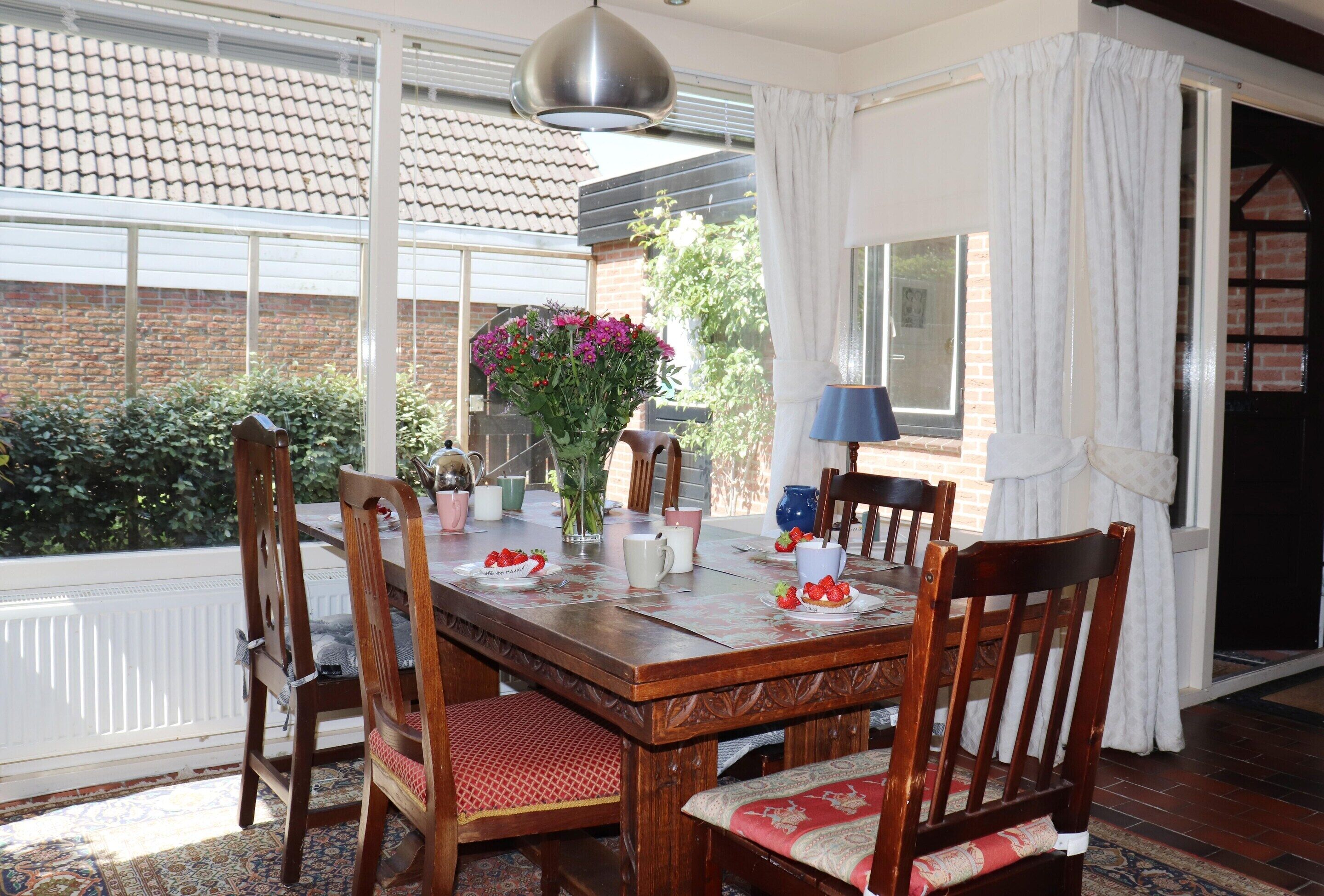 A dining table set with chairs, a vase with flowers, and a lamp.