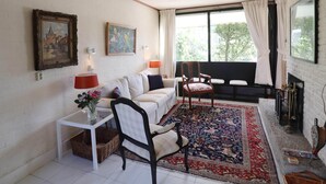 A cozy living room with a white sofa, a patterned rug, and a fireplace. - Holiday Home in Noordwijkerhout by Forest & Lake (Noordwijkerhout)